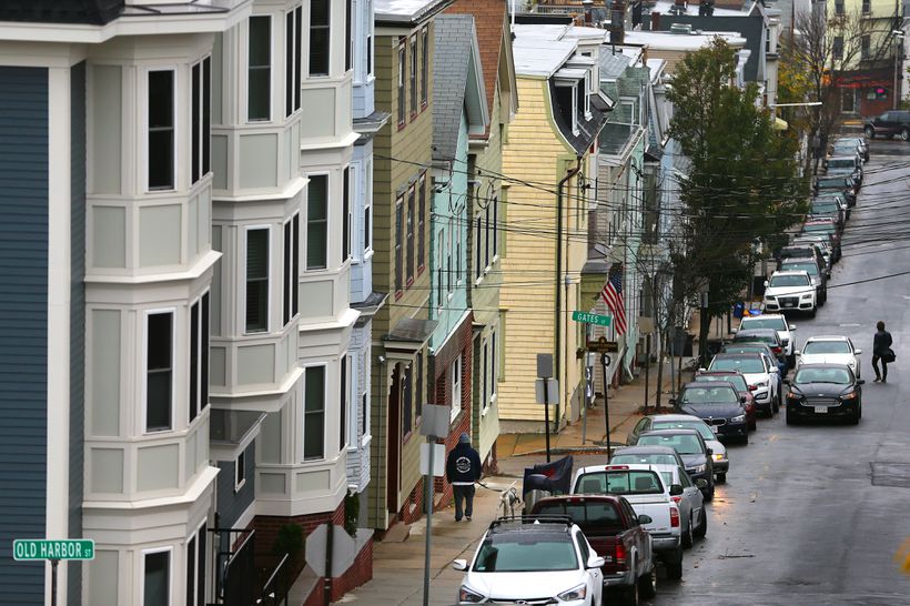 Photo angled down a street in Boston showing town houses and parked cars. Street signs for Gates St and Old Harbor St are visible, along with two residents walking.