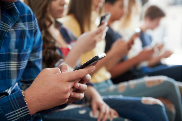 Close Up Of A Line Of High School Students Using Mobile Phones